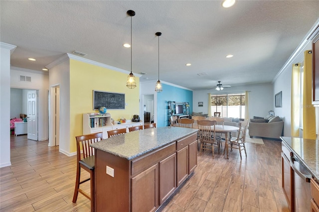 kitchen featuring visible vents, brown cabinets, a breakfast bar, light wood finished floors, and ceiling fan