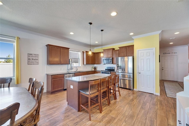 kitchen with a breakfast bar area, light wood-style flooring, a sink, appliances with stainless steel finishes, and a center island