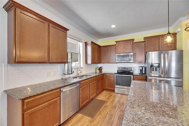 kitchen with light wood finished floors, tasteful backsplash, crown molding, appliances with stainless steel finishes, and a sink