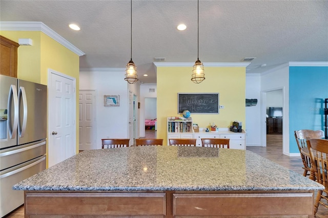 kitchen with brown cabinets, stainless steel refrigerator with ice dispenser, and light stone countertops