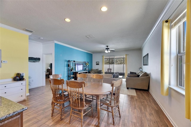 dining area with light wood-type flooring, a textured ceiling, visible vents, and a ceiling fan