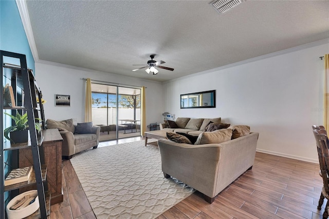 living room featuring visible vents, ornamental molding, a ceiling fan, a textured ceiling, and wood finished floors