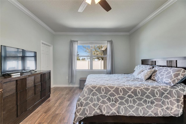 bedroom featuring a ceiling fan, crown molding, wood finished floors, and baseboards