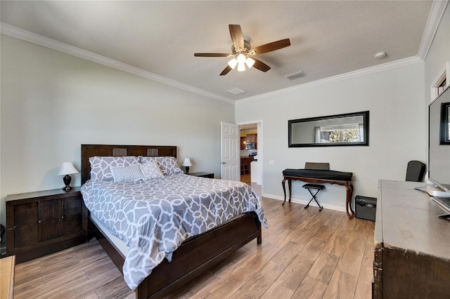 bedroom featuring baseboards, visible vents, light wood finished floors, and ornamental molding