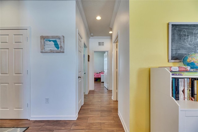 hallway with visible vents, recessed lighting, crown molding, baseboards, and wood tiled floor