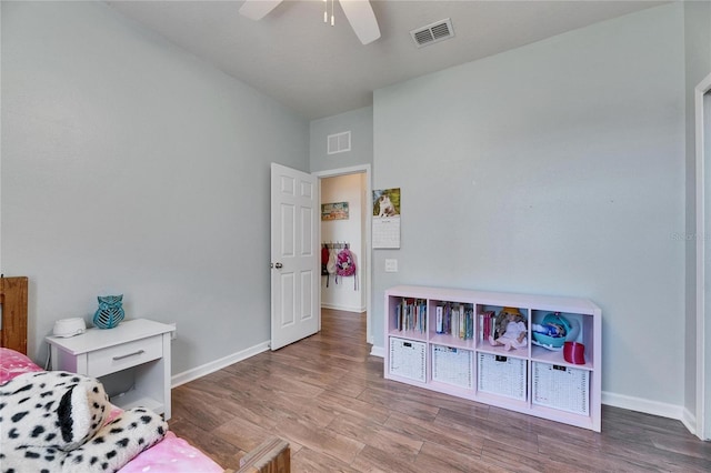 bedroom featuring visible vents, baseboards, wood finished floors, and a ceiling fan