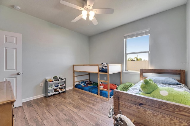 bedroom with ceiling fan, baseboards, and wood finished floors