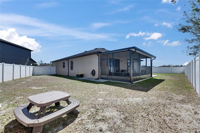 back of property with stucco siding, a fenced backyard, and a sunroom