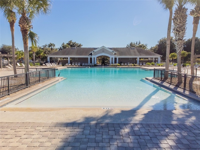 community pool with a patio area and fence