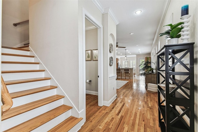 entryway featuring a ceiling fan, wood finished floors, stairway, crown molding, and baseboards