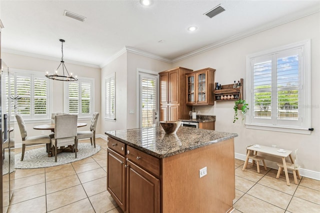 kitchen featuring visible vents, a center island, brown cabinetry, glass insert cabinets, and light tile patterned flooring