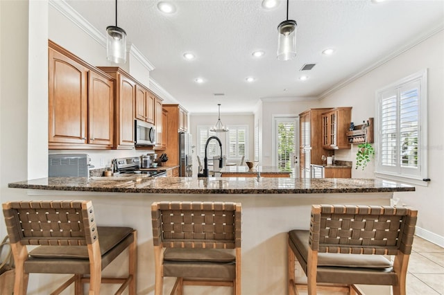 kitchen featuring dark stone counters, brown cabinetry, visible vents, and stainless steel appliances