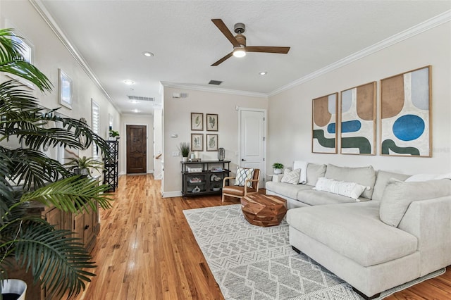 living area with visible vents, light wood-type flooring, and ornamental molding