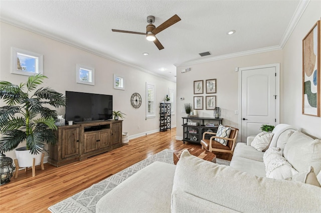 living room featuring visible vents, crown molding, baseboards, and wood finished floors