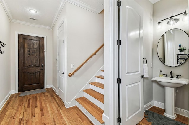 entryway featuring visible vents, light wood-style flooring, stairway, crown molding, and baseboards