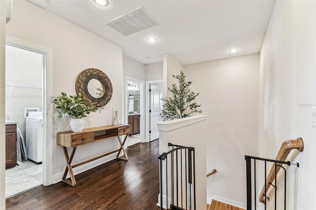 hall featuring an upstairs landing, visible vents, baseboards, and dark wood-style flooring