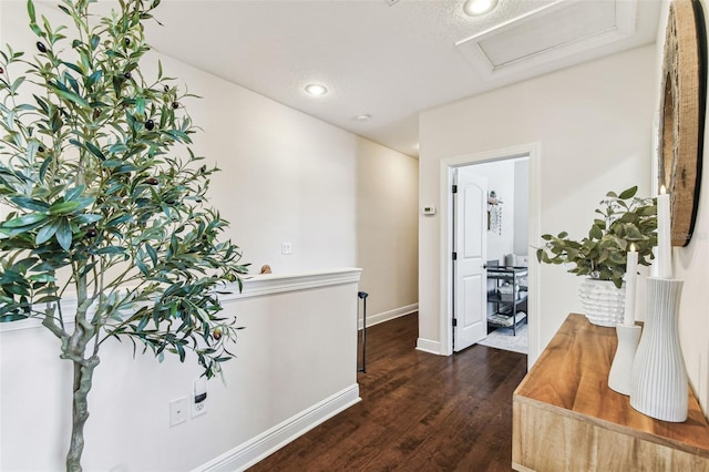 hallway with baseboards, attic access, and wood finished floors