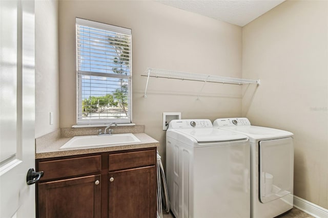 clothes washing area featuring washer and clothes dryer, cabinet space, and a sink