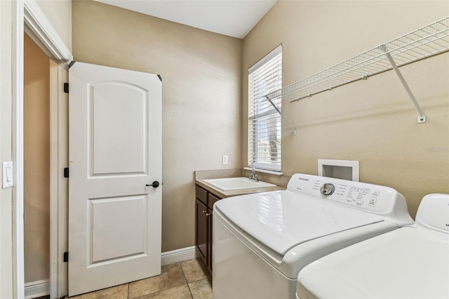 washroom with washing machine and clothes dryer, baseboards, light tile patterned flooring, cabinet space, and a sink