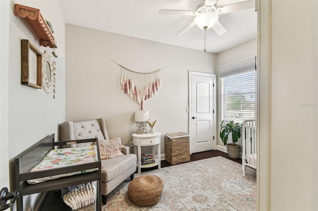 sitting room with baseboards, a textured ceiling, wood finished floors, and a ceiling fan