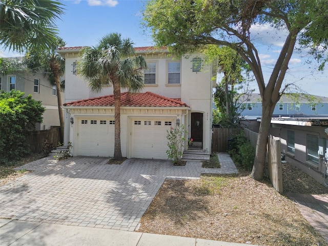 view of front of house with decorative driveway, fence, stucco siding, and a tile roof