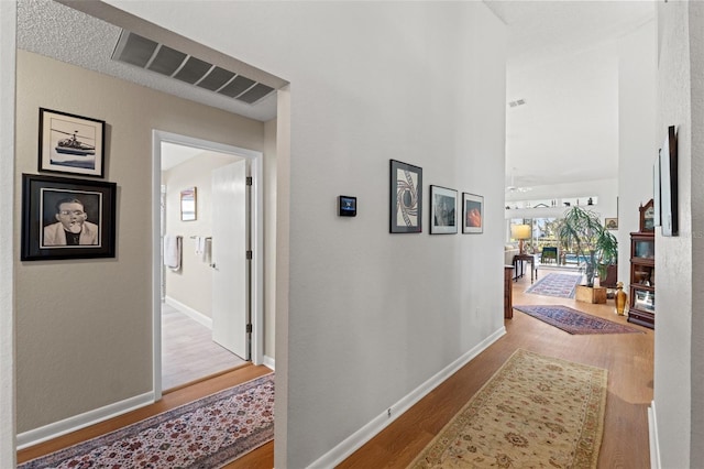 corridor with visible vents, baseboards, and wood finished floors