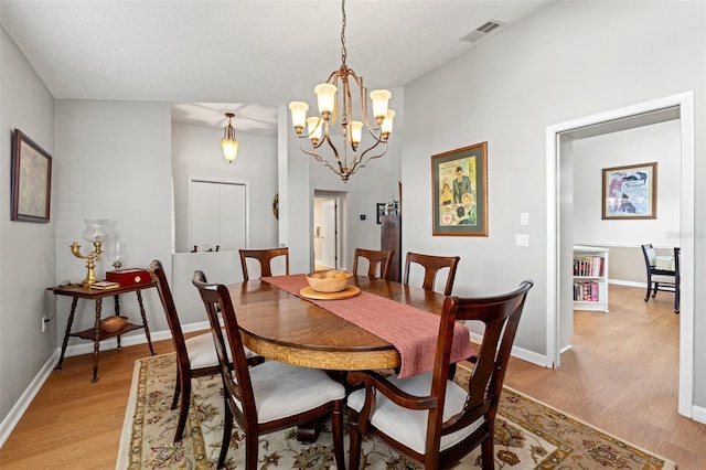 dining room with light wood-style flooring, baseboards, visible vents, and a chandelier