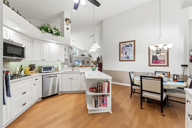 kitchen featuring a sink, ceiling fan with notable chandelier, appliances with stainless steel finishes, a peninsula, and open shelves