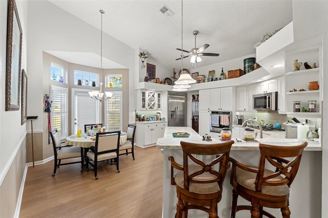 kitchen featuring light wood finished floors, appliances with stainless steel finishes, a peninsula, white cabinets, and open shelves