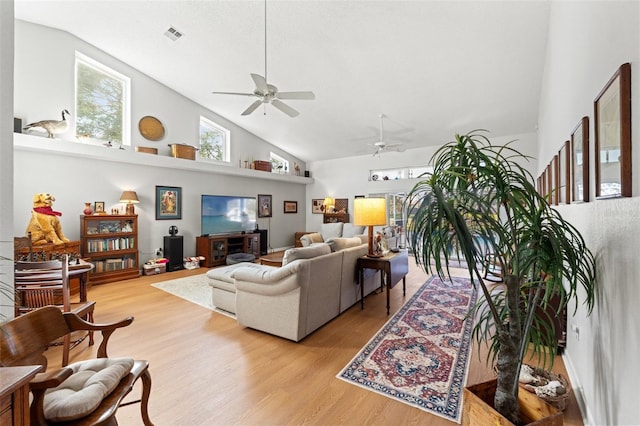 living room with ceiling fan, visible vents, light wood-type flooring, and high vaulted ceiling