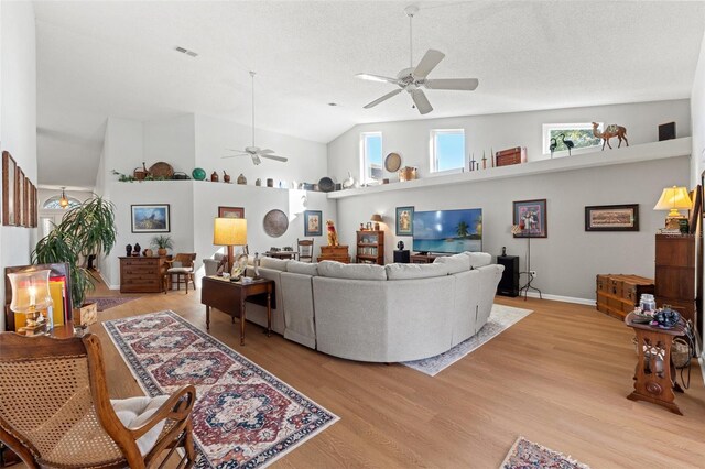 living room with light wood-type flooring, visible vents, high vaulted ceiling, a textured ceiling, and ceiling fan