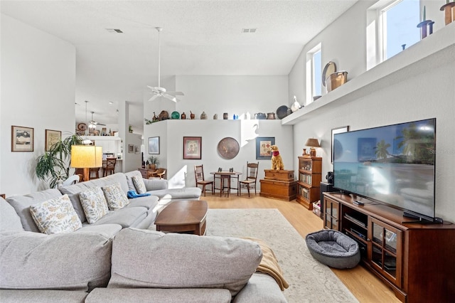 living room with visible vents, light wood-style floors, and a high ceiling