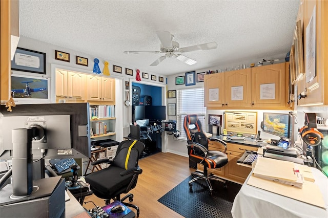 home office with a textured ceiling, a ceiling fan, and light wood-style floors