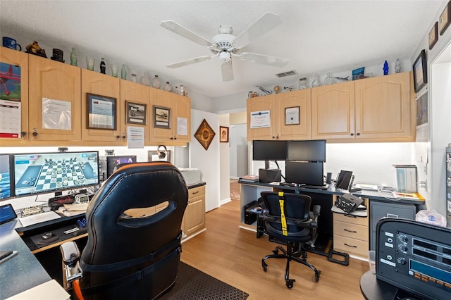 office area with a ceiling fan, visible vents, built in study area, a textured ceiling, and light wood-type flooring