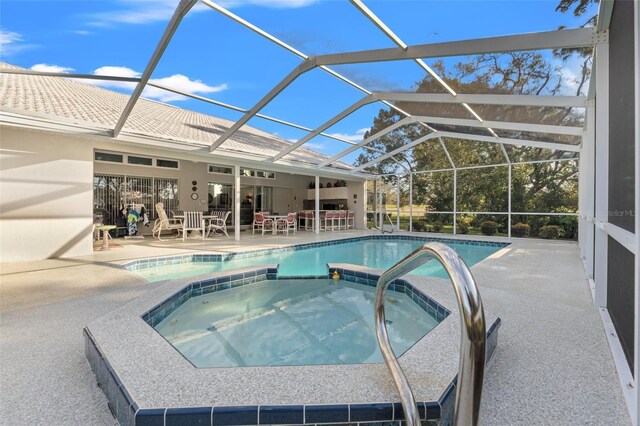 view of swimming pool featuring glass enclosure, a pool with connected hot tub, and a patio area