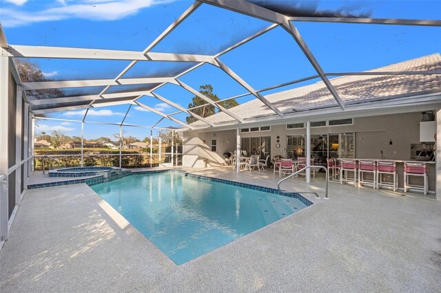 view of pool with glass enclosure, a patio, outdoor dry bar, and a pool with connected hot tub