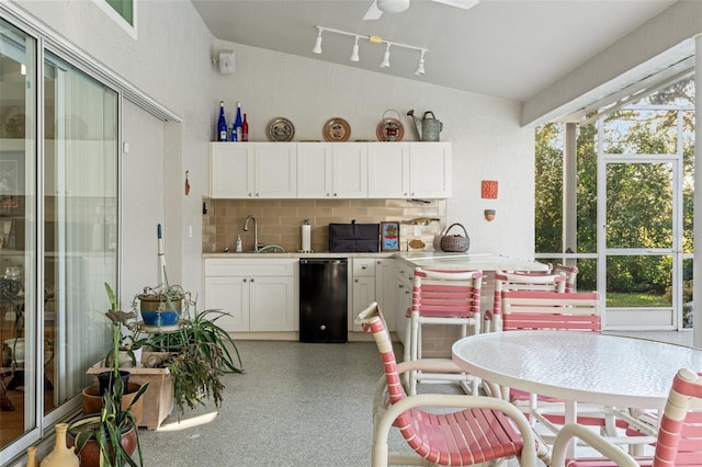 kitchen featuring a sink, backsplash, white cabinets, light countertops, and vaulted ceiling