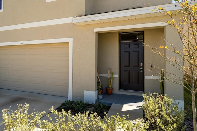 view of exterior entry featuring stucco siding and driveway