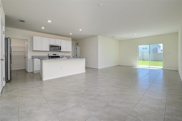 kitchen featuring visible vents, a center island with sink, open floor plan, white cabinetry, and appliances with stainless steel finishes