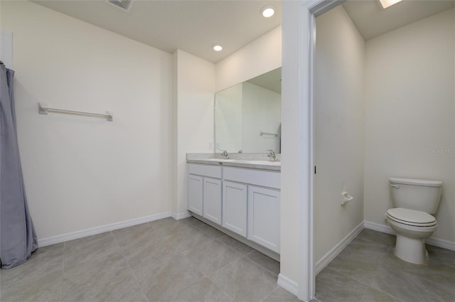 bathroom featuring double vanity, toilet, baseboards, and a sink