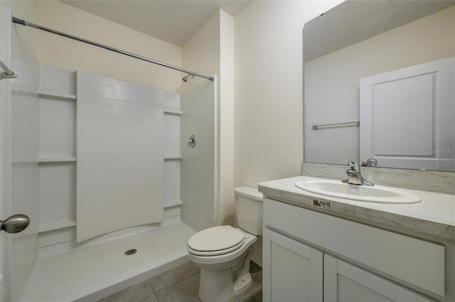 bathroom featuring toilet, a stall shower, vanity, and tile patterned flooring