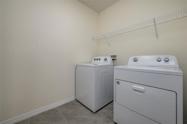 washroom with washing machine and clothes dryer, laundry area, baseboards, and light tile patterned floors