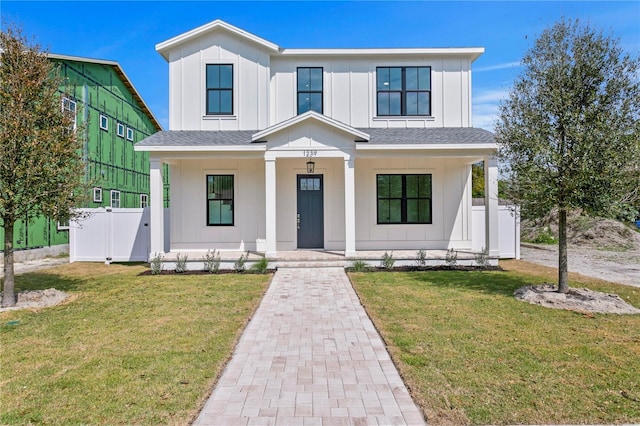 modern inspired farmhouse featuring covered porch, board and batten siding, a front yard, and fence