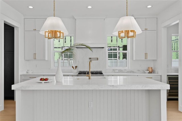 kitchen with wine cooler, recessed lighting, an island with sink, and premium range hood