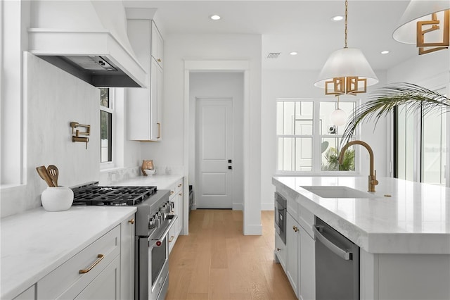 kitchen with custom exhaust hood, plenty of natural light, stainless steel appliances, and a sink