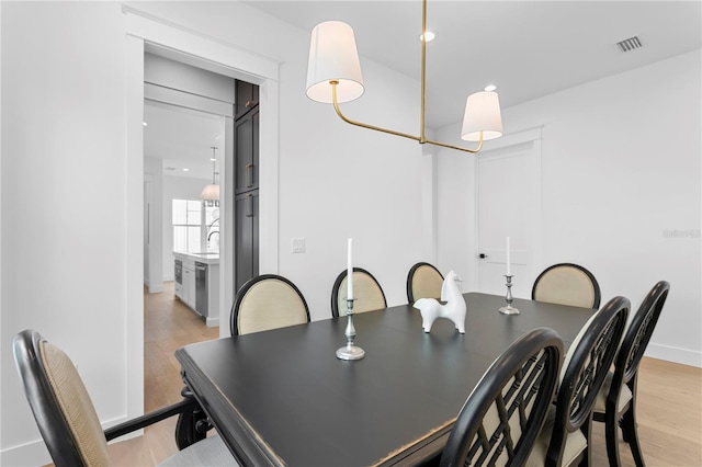 dining space featuring light wood-style floors, visible vents, and baseboards