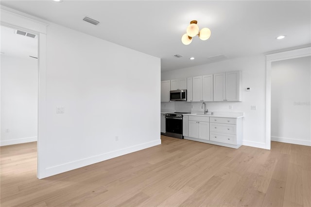 kitchen with light wood-type flooring, stainless steel appliances, baseboards, and light countertops