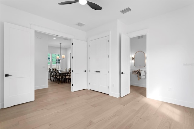 interior space with visible vents, baseboards, light wood-style floors, and a ceiling fan