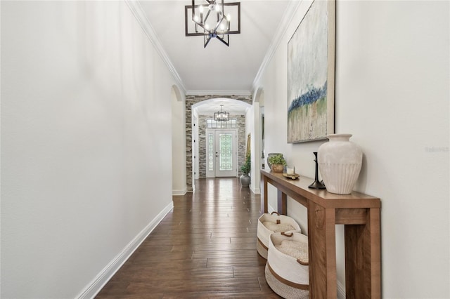 corridor with crown molding, baseboards, a chandelier, dark wood finished floors, and arched walkways