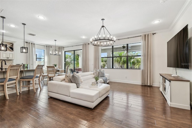 living area featuring visible vents, dark wood-type flooring, an inviting chandelier, and ornamental molding